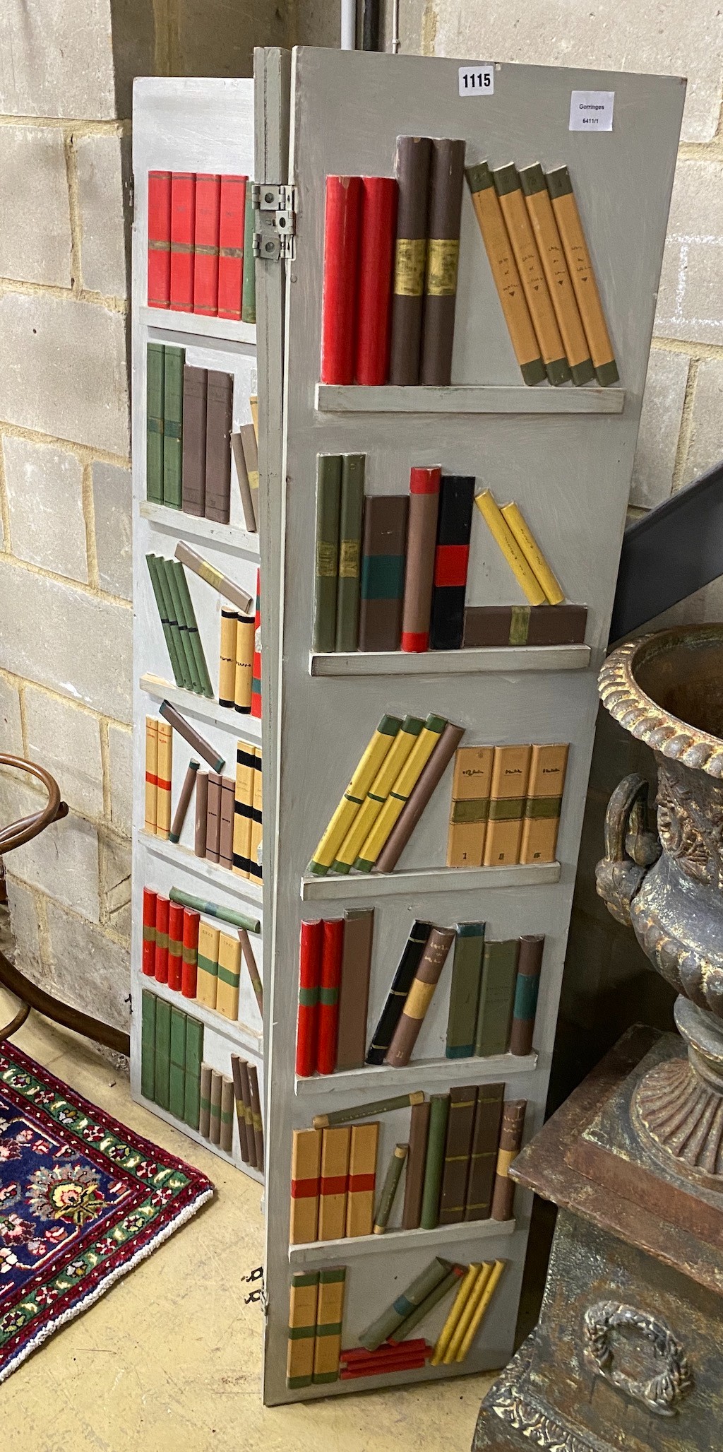 A painted wood three fold dressing screen modelled as a bookcase by Georges Liotard, each panel width 36cm, height 165cm